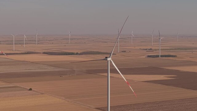 Sideways Aerial Pass Along Wind Turbines on an Open Farming Plain