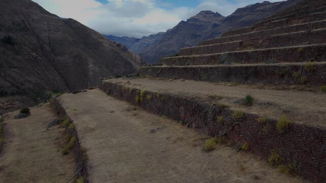 Wide angle view of ancient Inca agricultural stone terraces carved into a steep mountain slope in Peru. Historic Andean ruins, rugged valley landscape, daytime archaeological travel b-roll.
