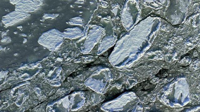 Aerial top-down drone shot of the frozen surface of the Bay of Gdańsk with cracked sea ice, Baltic Sea, Poland, in winter
