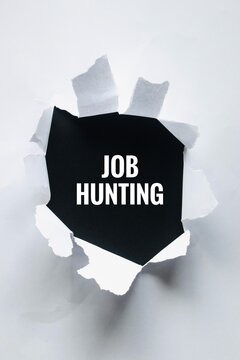 Conceptual image showing the words "JOB HUNTING" printed on a black background framed by a hole torn through white paper.