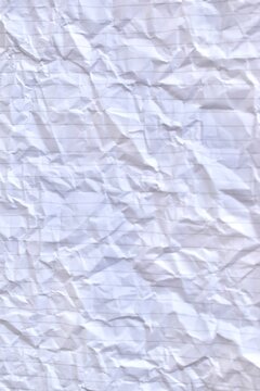 Close-up full-frame texture background of crumpled white lined notebook paper with creased folds and horizontal rules.