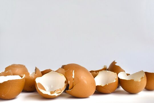 A collection of cracked brown eggshells isolated on a plain white background.