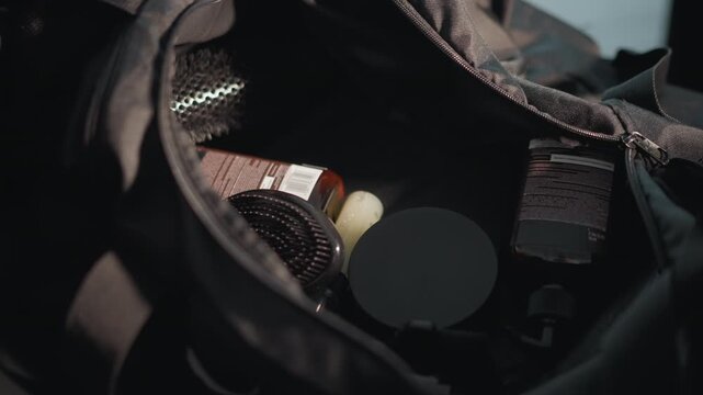 Close up view of open bag containing hair styling tools and products such as brush bottle likely shampoo or product lens cap. scene focuses on contents without visible human subjects