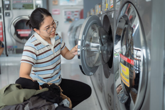 Asian people using qualified coin operated laundry machine in the public room to wash their cloths. Concept of a self service commercial laundry and drying machine in a public room