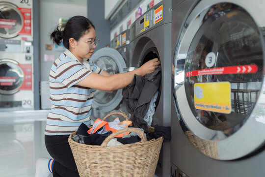Asian people using qualified coin operated laundry machine in the public room to wash their cloths. Concept of a self service commercial laundry and drying machine in a public room