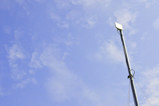 Wireless WiFi receiver antenna on a pole against a clear blue sky background