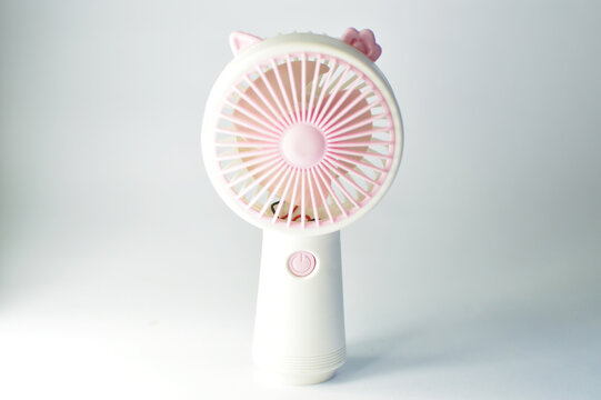 Pink portable mini handheld electric fan isolated on soft background
