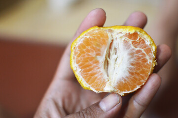 Close up of a hand peeling a fresh and ripe orange fruit © shalahuddin