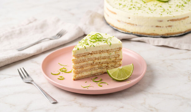 Traditional Mexican Carlota de Limon:  Carlota de Limon icebox cake. The clean cut reveals alternate layers of tangy lime-infused condensed milk cream and thin Maria biscuits. The slice rests on a mod