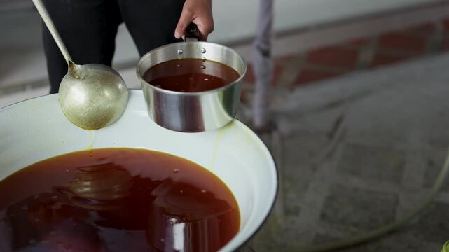Scooping Melted Candle Wax from Large Basin with Ladle