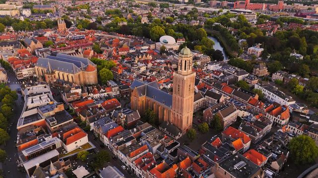 Golden-hour aerial of Zwolle, Netherlands, with the Peperbus tower and Grote Kerk rising above dense historic streets, canals and red-tiled buildings.