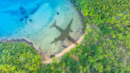 Naklejka premium Aerial view of shadow passenger plane silhouette and sandy beach blue sea with waves at sea beach summer vacation sea travel concept 