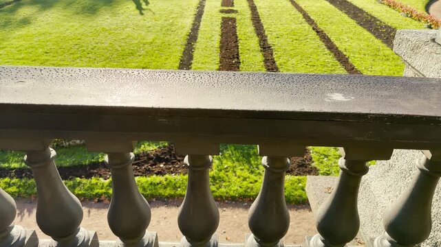 Tracking shot of an empty dew-covered balustrade on gimbal in Catherine Park, Pushkin, Saint Petersburg. Smooth sideways camera movement, no people, evoking peaceful, serene feelings.