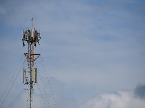 Cell phone tower site or cell base tower or cellular base station with white cloud and blue sky in background