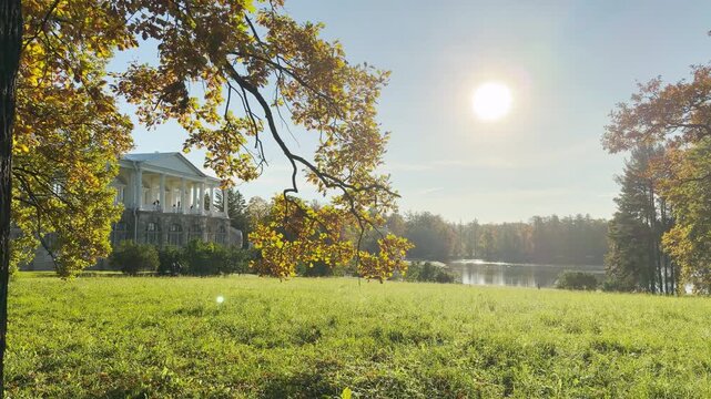 Tracking shot of an empty park on gimbal. Smooth sideways camera movement reveals the Cameron Gallery and lake in Catherine Park, Pushkin, Saint Petersburg, evoking deep peace.