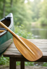 Fototapeta premium Outdoor recreation and adventure travel, wooden canoe paddle resting on a wooden dock by a calm lake in the forest for summer vacation and leisure