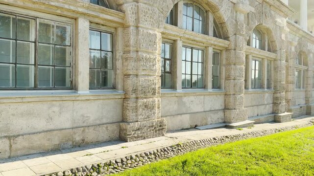 Tracking shot of an empty stone wall on gimbal. Smooth sideways camera movement reveals the Cameron Gallery in Catherine Park, Pushkin, Saint Petersburg, evoking deep peace.