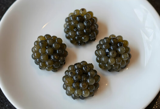 Gastronomy and molecular cuisine, spheres of olive oil or balsamic vinegar pearls served on a white plate for fine dining and luxury food plating