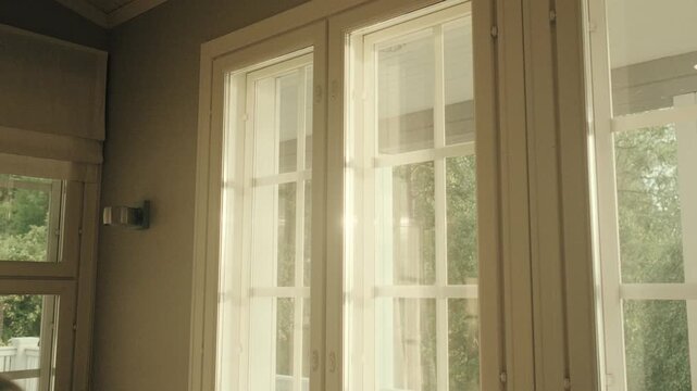 Sunlight streams through classic wooden framed windows, illuminating the tranquil interior of a rustic countryside cabin. Soft, natural light highlights serene decor and peaceful retreat ambiance.