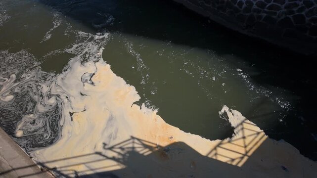 Abstract dark water surface with swirling foam and soft oily patterns, creating a texture background. Steady shot.