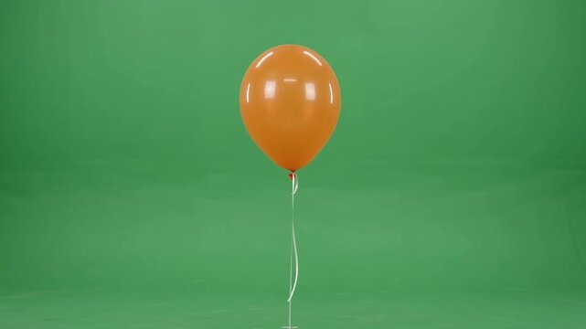 Single orange party balloon floating isolated on a green screen background isolated object decoration inflatable birthday event
