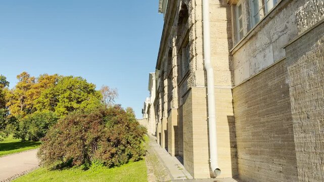 A majestic historic palace facade stands peacefully in Catherine Park, Pushkin, Saint Petersburg. A smooth pan shot captures the calm, serene beauty of the sunny architecture and lush greenery.