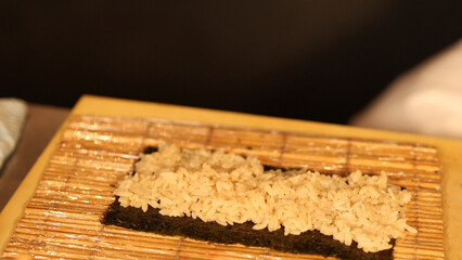 Seasoned Rice Spread on Nori Sheet on Bamboo Mat © blueringmedia