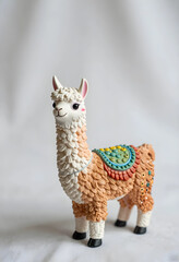 Fototapeta premium Childhood play and imagination, cute llama toy figurine with colorful saddle for nursery decor and creative storytelling in a studio setting