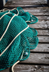 Fototapeta premium Sustainable fishing and marine conservation, commercial fishing net with weights resting on a weathered wooden pier at a harbor for maritime industry