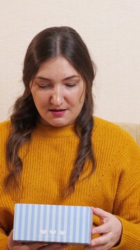 Curious young woman in a yellow sweater opening a gift box, her initial excitement turning into shock, disappointment, and disgust as she discovers an unwanted and unpleasant surprise inside