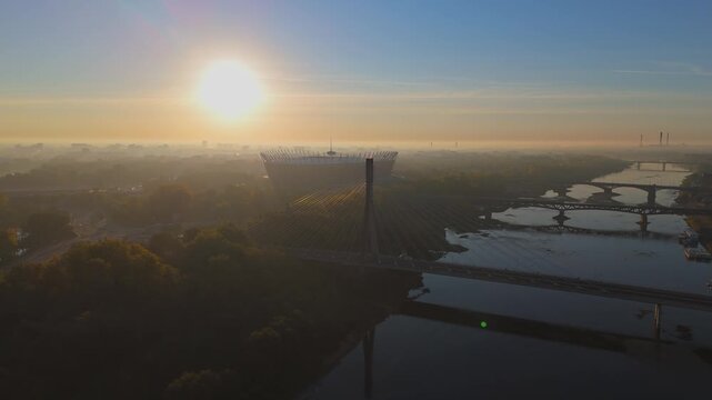 Aerial Drone Footage of Warsaw Cityscape at Sunrise featuring National Stadium, Bridges, and Vistula River