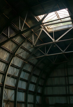 Urban decay and industrial decline, abandoned warehouse interior with corrugated metal roof and natural light streaming through a broken skylight