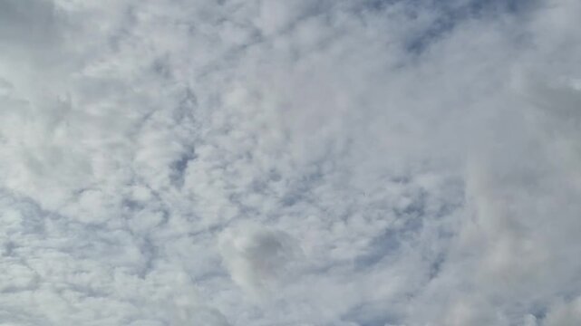 Dramatic cloudscape signals impending weather change across vast troposphere. Fluffy cumulus masses merge with darker overcast layers creating moody natural sky ambience.