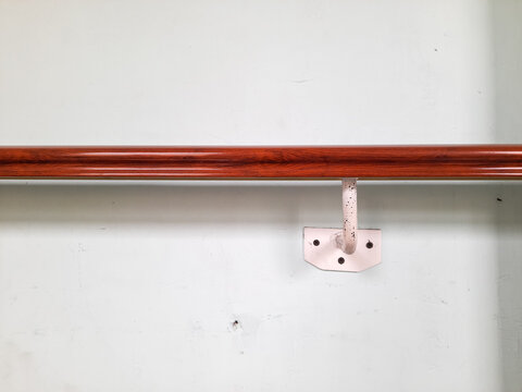 A safety handrail made of wood, polished to a high shine and securely mounted to the wall using metal support brackets