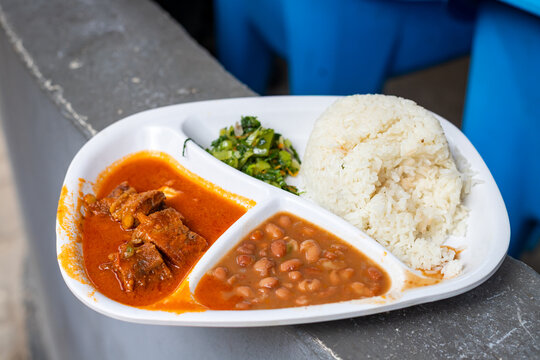 traditional Tanzanian rice dish plate served with beef stew, cooked beans, and mchicha sauteed leafy greens at a local eatery in Dar es Salaam, Tanzania.