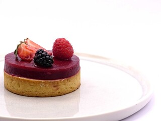 Gourmet red berry tartlet with fresh berries served on white plate © Dimitri