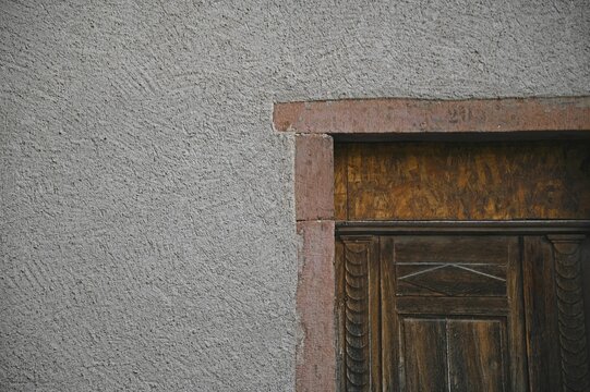 Antique rural house oak wooden door with a stone trim on a textured wall in Bergheim, Alsace France.