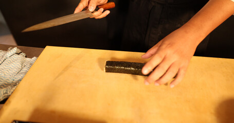 Sushi Chef Preparing to Slice a Fresh Nori Roll With Knife © blueringmedia