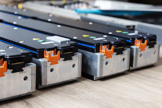 Electric Vehicle Battery Modules with Orange Connectors on a Workbench