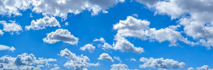 Fototapeta premium Beautiful blue sky background with cumulus clouds. Large and small vapor structures are arranged in a chain, flowing smoothly along the horizon. Wide website banner.