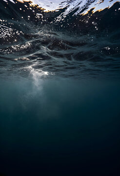 Ocean depth and serenity, underwater view of sunlight rays piercing through dark blue sea surface with calm water ripples and abstract light reflections