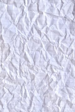 Close-up full-frame texture background of crumpled white lined notebook paper with creased folds and horizontal rules.