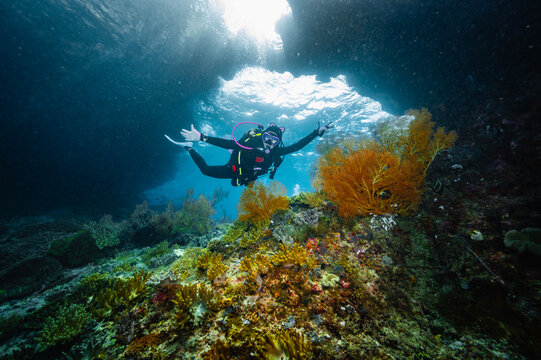 Happy woman scuba diving near a colorful reef
