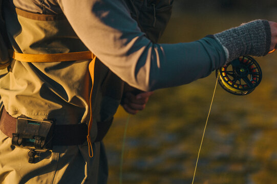 Close view of an angler holding a fly rod and reel.