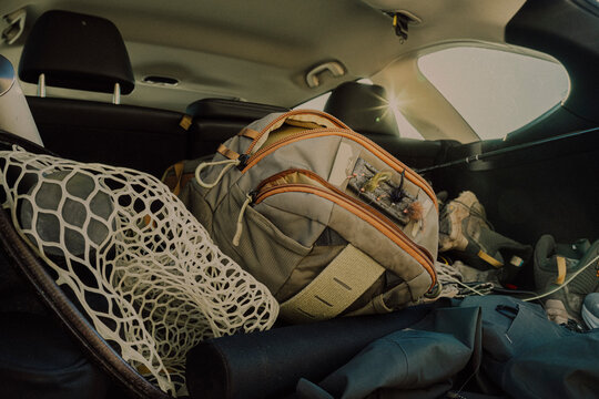 Fly fishing gear and landing net packed inside the back of a vehicle.