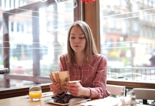 A young woman counts banknotes in a bar.