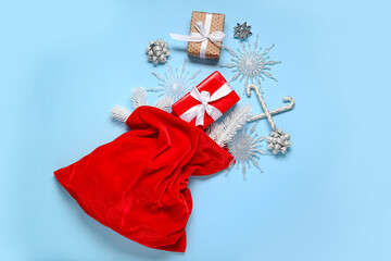 Fototapeta premium Santa bag with gift boxes, decorative snowflakes and candy canes on blue background