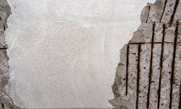A close up view of structural concrete decay showing spalled cement layers and heavily rusted iron reinforcement bars requiring concrete restoration