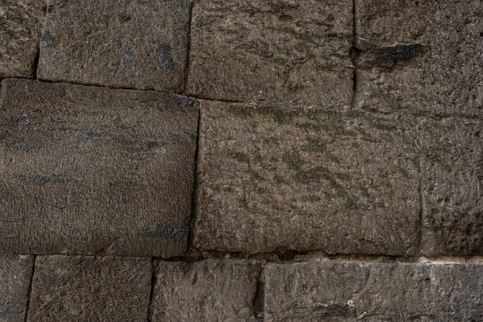 Close up full frame background texture of rustic rough hewn stone masonry blocks weathered by time with authentic architectural stone detailing