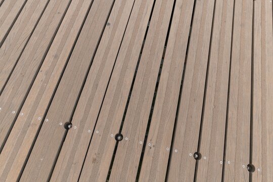 Close up view of parallel composite timber deck planks installed on an outdoor terrace floor showing linear groove patterns and wood texture